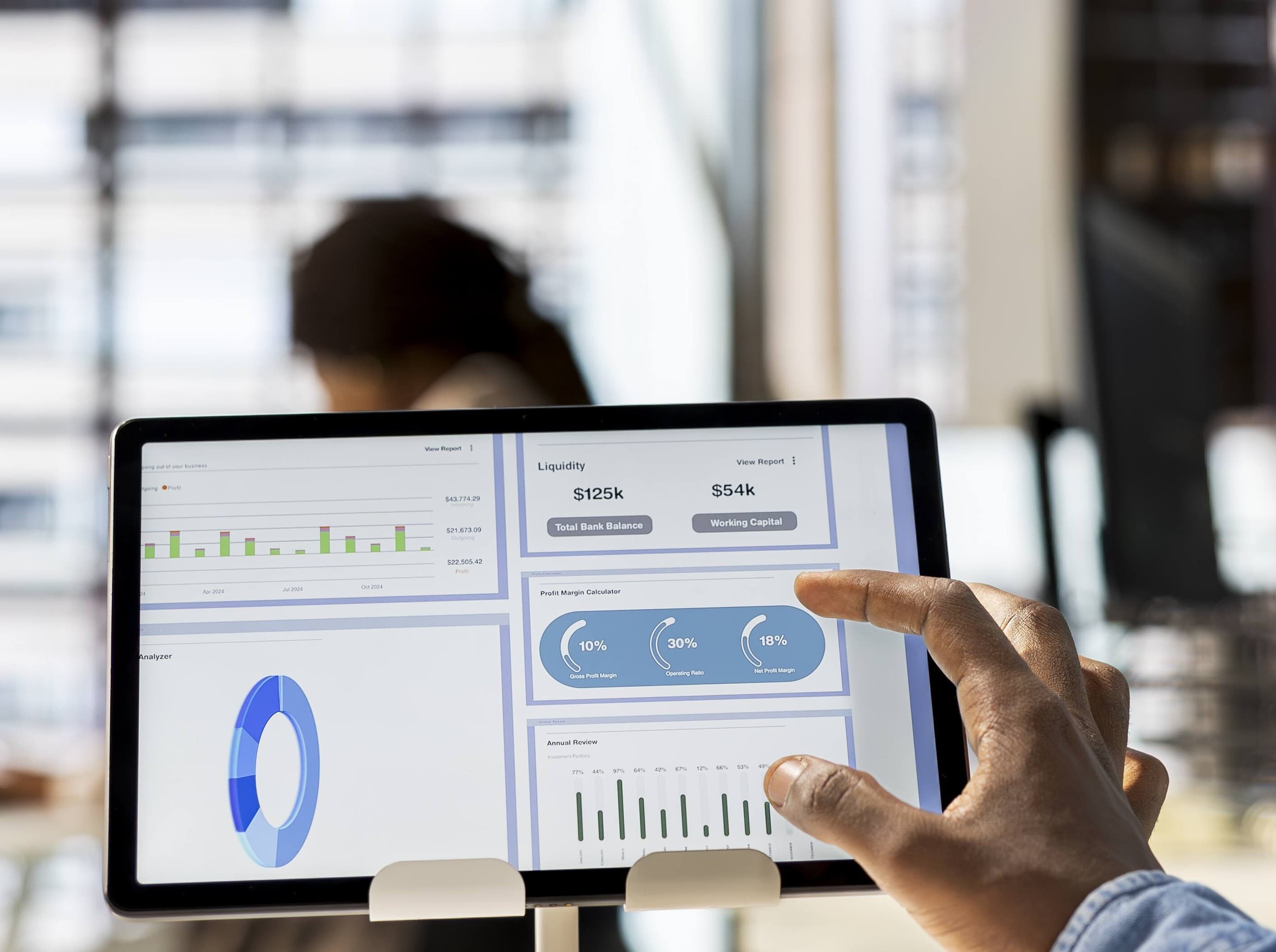 A person reviewing business performance charts and reports on a tablet