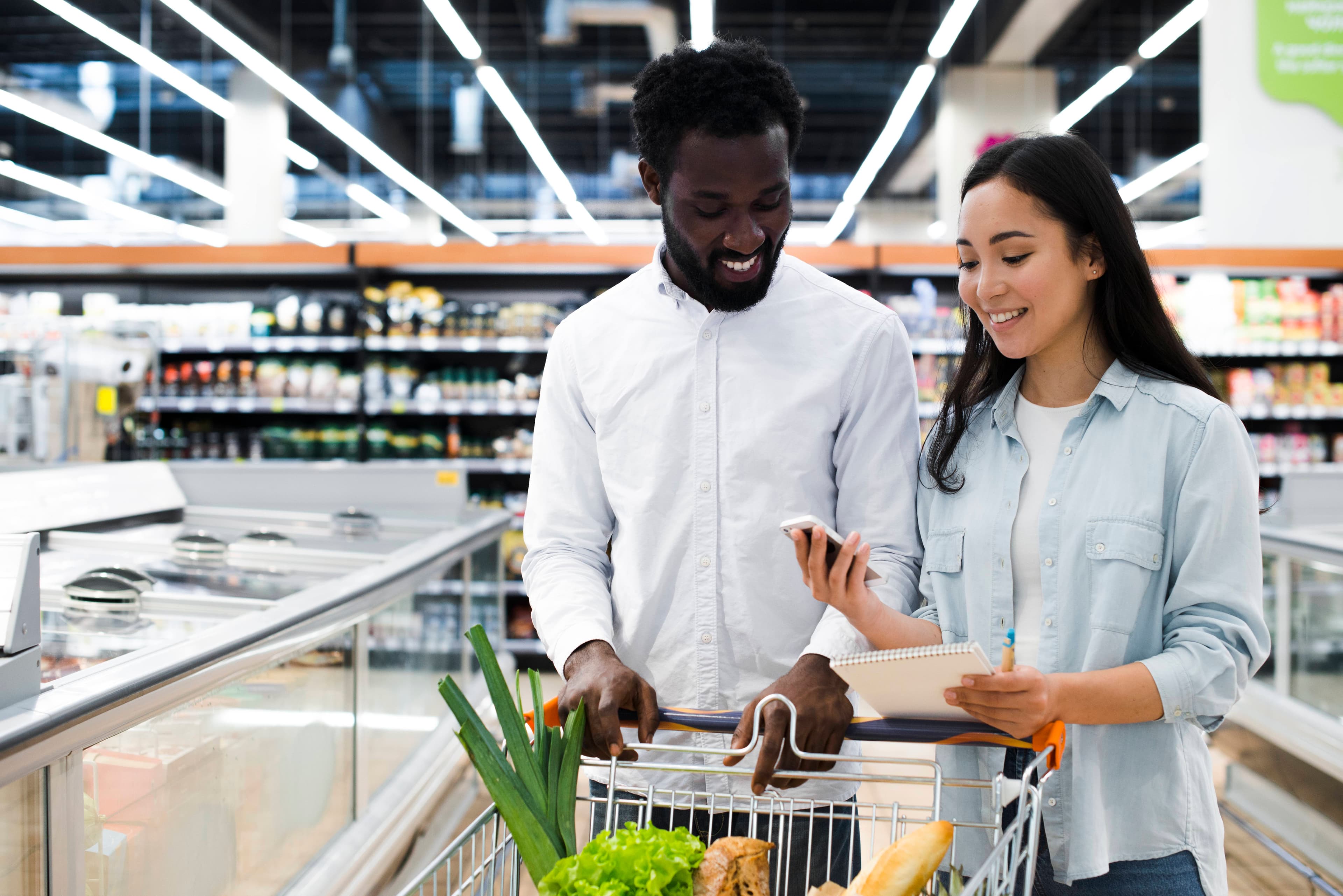 Customers using a phone while shopping in a supermarket